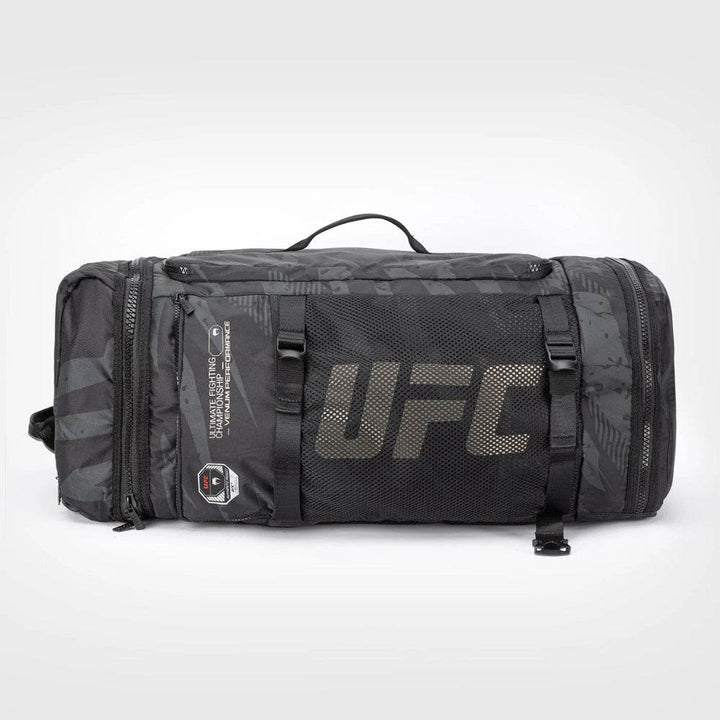Back view of the UFC Fight Week Performance Kit sport bag by Venum featuring a large black mesh panel with bold UFC branding, side zippered compartments, and reinforced carry handle.