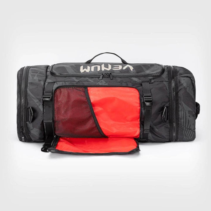 Front view of the UFC Fight Week Performance Kit bag with the external pocket unzipped to reveal a vibrant red interior and mesh divider for organized gear storage.