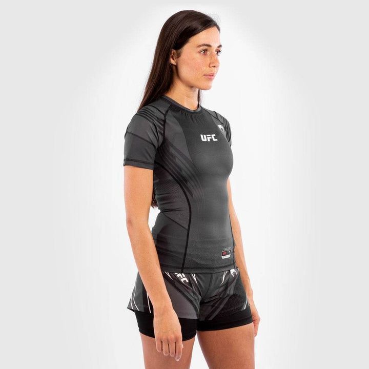 Side profile of woman in black Venum UFC rash guard and shorts.