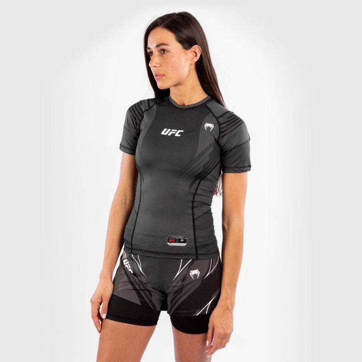 Full-body shot of woman in UFC Venum rash guard and training shorts.