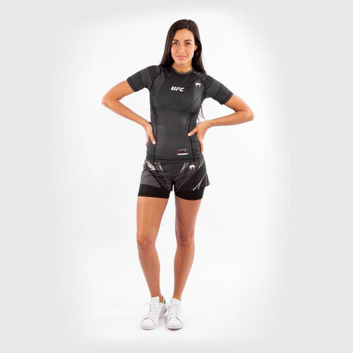 Full-body shot of woman in UFC Venum rash guard and training shorts.
