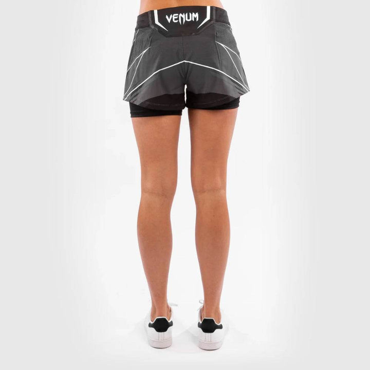 Back view of the UFC women's fightshorts featuring a curved cut hem and white Venum logo on the waistband, emphasizing athletic design and movement range.