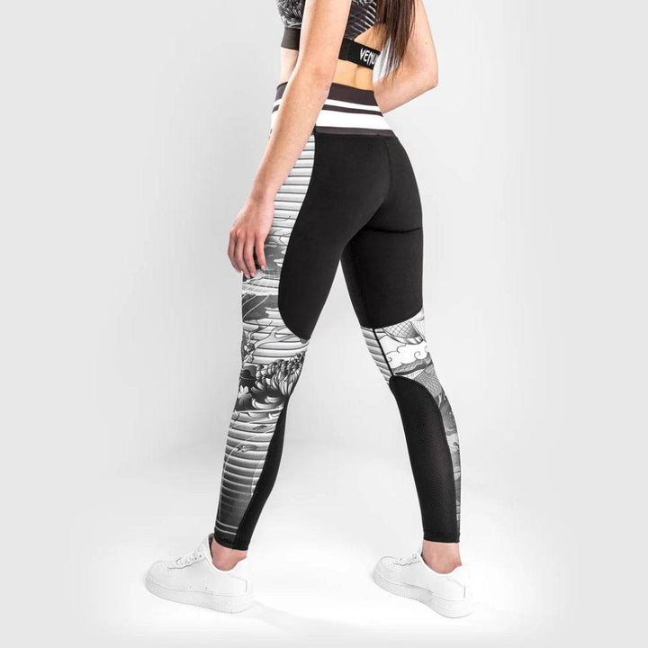 Rear three-quarter view of the leggings featuring intricate artwork and contrasting mesh inserts.